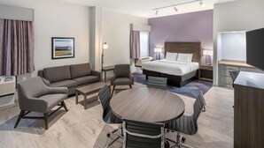 A modern hotel room with a bed, sofa, dining table, chairs, and a desk. - Best Western Hickory (Hickory)