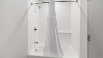 A modern bathroom with a shower curtain, a bathtub, and a toilet.