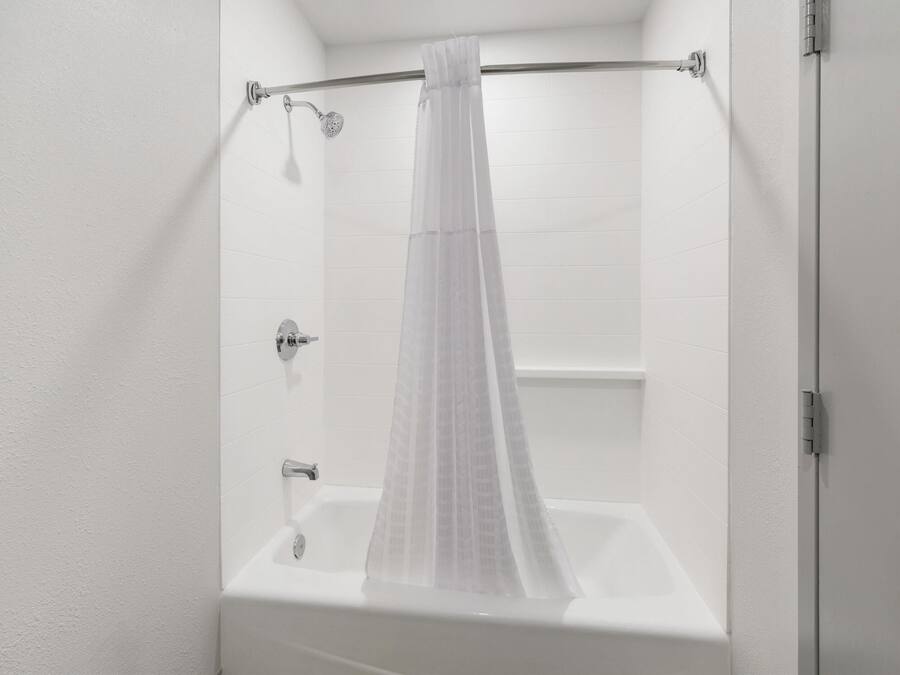 Une salle de bain moderne avec un rideau de douche, une baignoire et des toilettes.