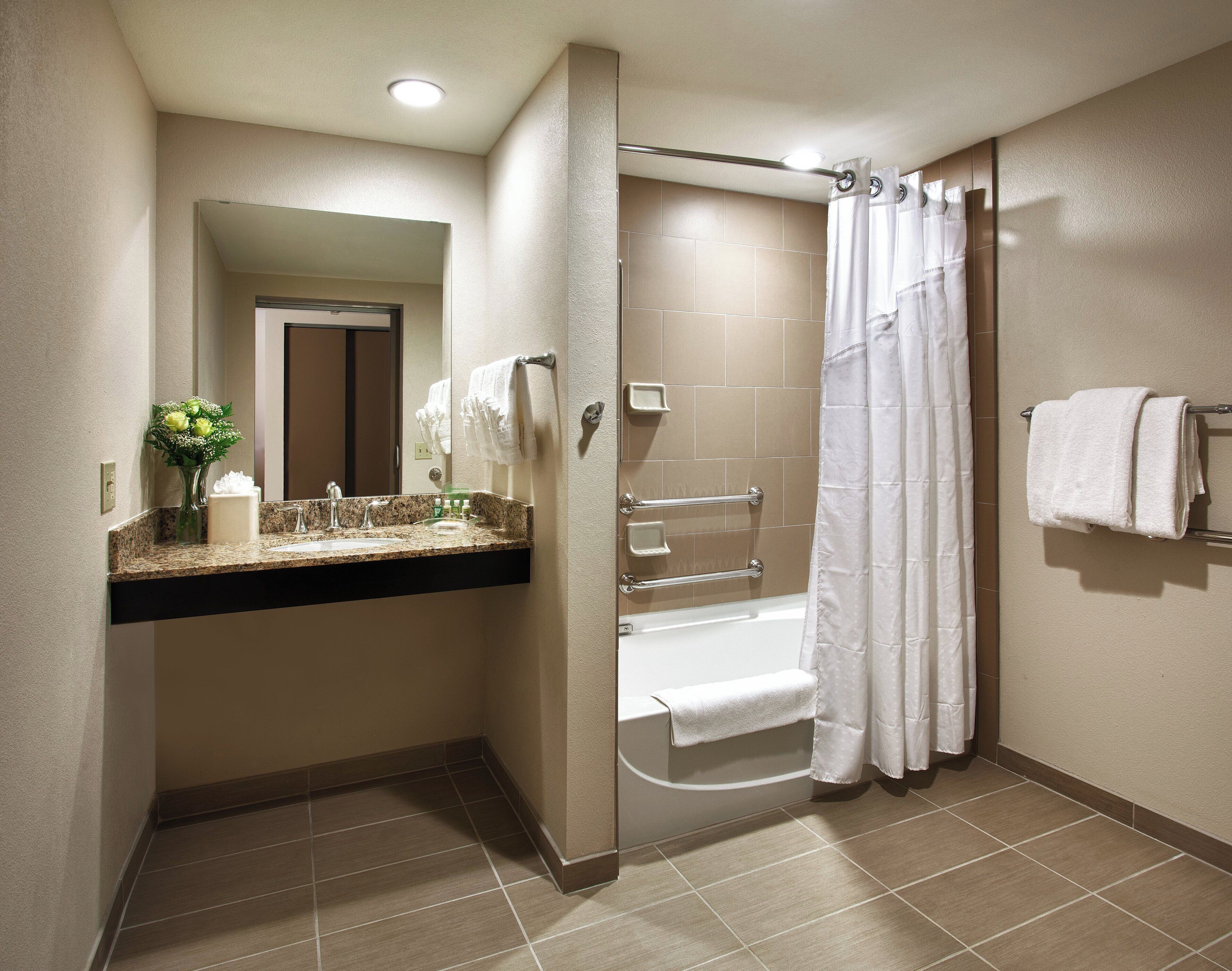 A modern bathroom with a glass-enclosed shower, a vanity with a marble countertop, and a mirror.