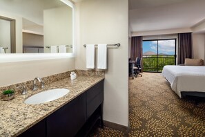 A hotel room with a granite countertop sink, a large mirror, a bed with a patterned carpet, and a view of a mountain through a balcony. - Holiday Inn & Suites Phoenix Airport North by IHG (Phoenix)