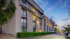A multi-story hotel with balconies, a parking lot, and a landscaped area. - Holiday Inn & Suites Phoenix Airport North by IHG (Phoenix)