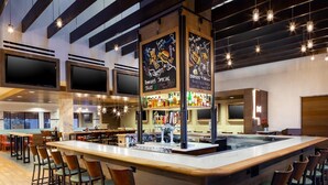 Zona de bar moderna con una barra central, taburetes y una variedad de bebidas.