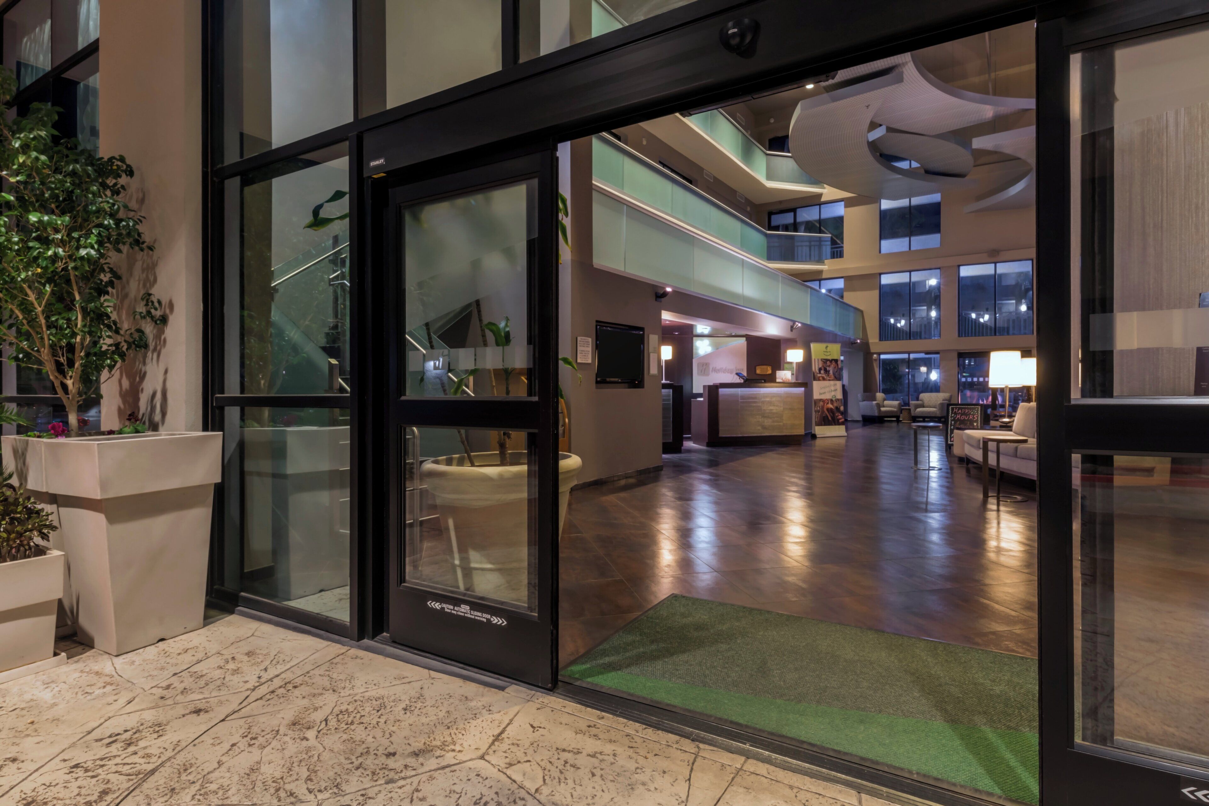 Un vestíbulo de hotel con entrada de vidrio, mostrador de recepción y diseño de interiores moderno.