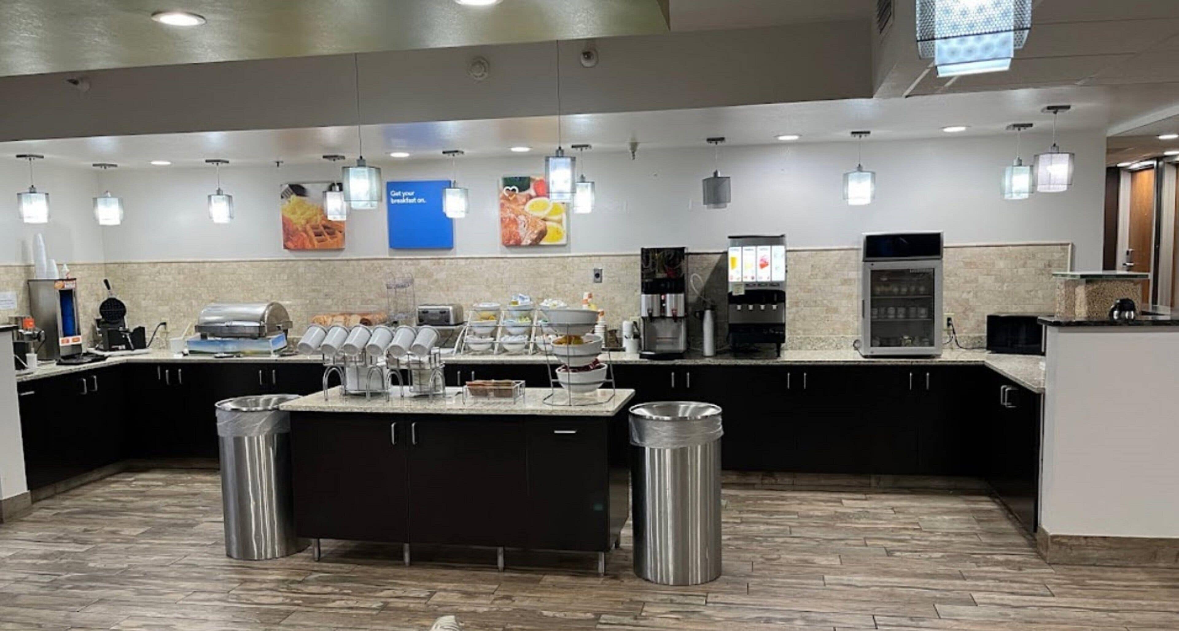 Una cocina moderna con una isla central, varias máquinas de café y una zona de estar.