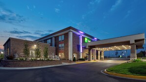A hotel with a brick facade, a green sign, and a covered parking area. - Holiday Inn Express & Suites Eden Prairie – Minneapolis by IHG (Eden Prairie)