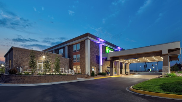 A hotel with a brick facade, a green sign, and a covered parking area.