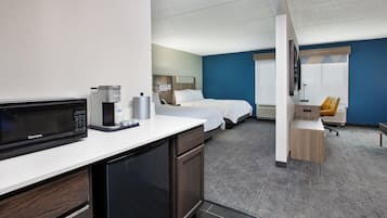 Una habitación de hotel con kitchenette, una cama, un escritorio y baño.