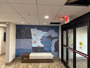 A lobby with a map mural, a reception desk, and emergency exit signs.