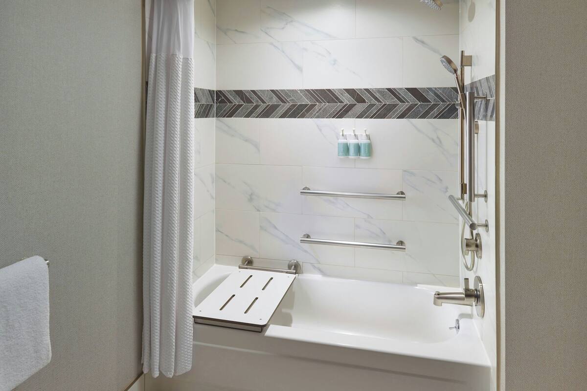 Une salle de bain avec une baignoire, une douche et un porte-serviettes.