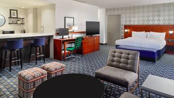 Habitación de hotel con cama, escritorio con computadora, una silla, una mesita y una zona de bar.
