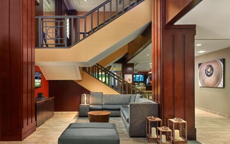 A modern lobby with a staircase, seating area, and a large artwork on the wall.