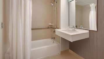 A modern bathroom with a bathtub, shower, and a vanity with a mirror.
