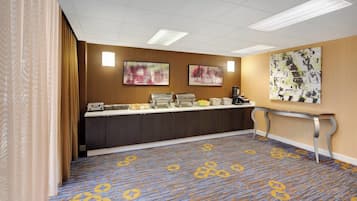 A hotel reception area with a counter, a coffee station, and artwork on the walls.