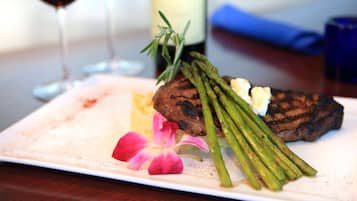 A plate with grilled steak, asparagus, and a flower on a white plate.