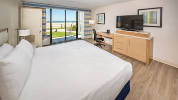 Una habitación de hotel con una cama grande, un escritorio, un televisor y vistas a la playa.