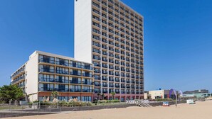 Un hotel alt amb nombrosos balcons i una vista despejada de la platja.