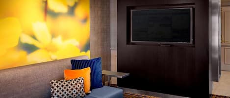 A modern lobby with a blue sofa, patterned pillows, a large abstract painting, a dark wooden door, and a small table.