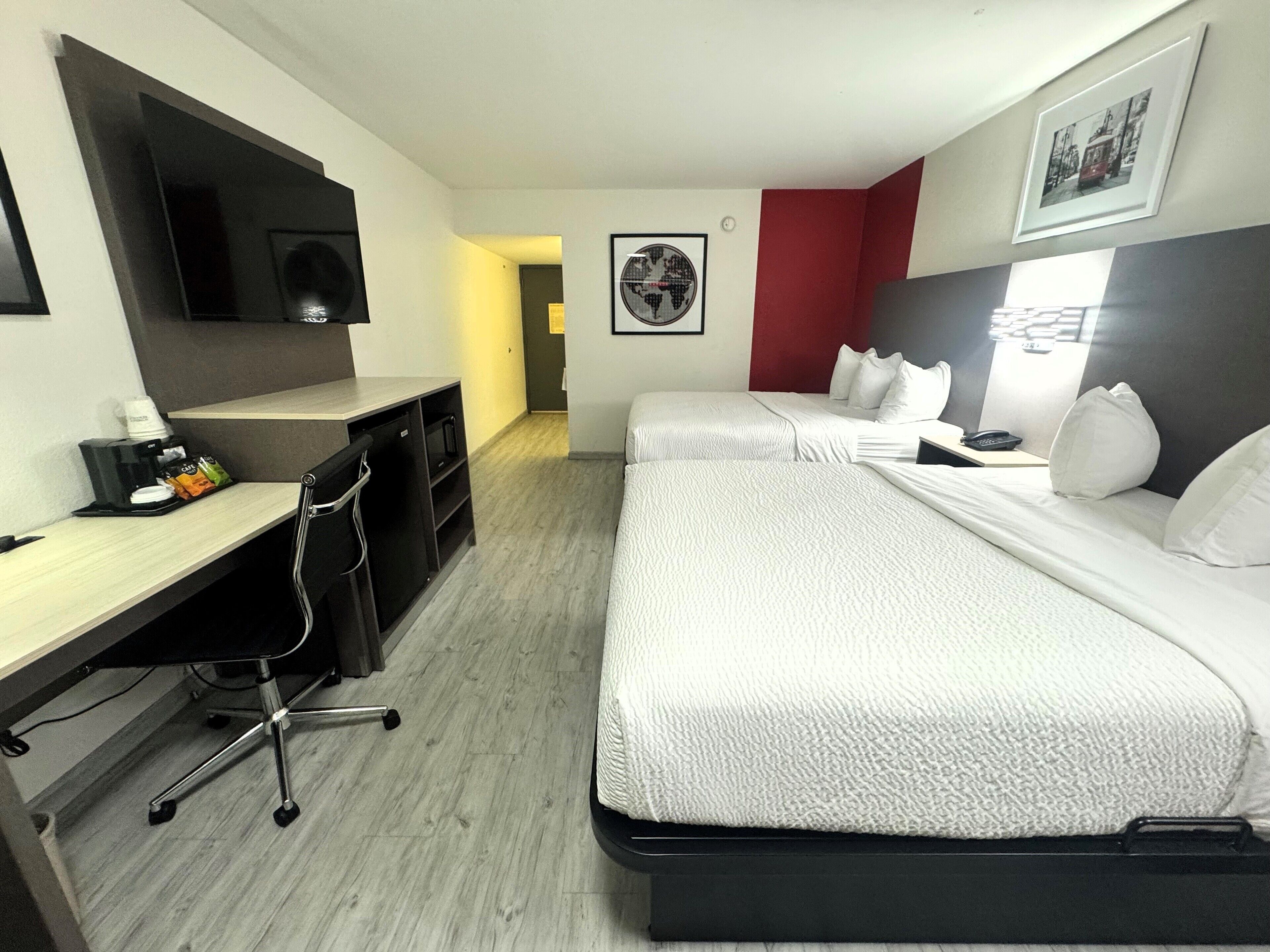 Una habitación de hotel con cama, escritorio, cafetera y televisión.