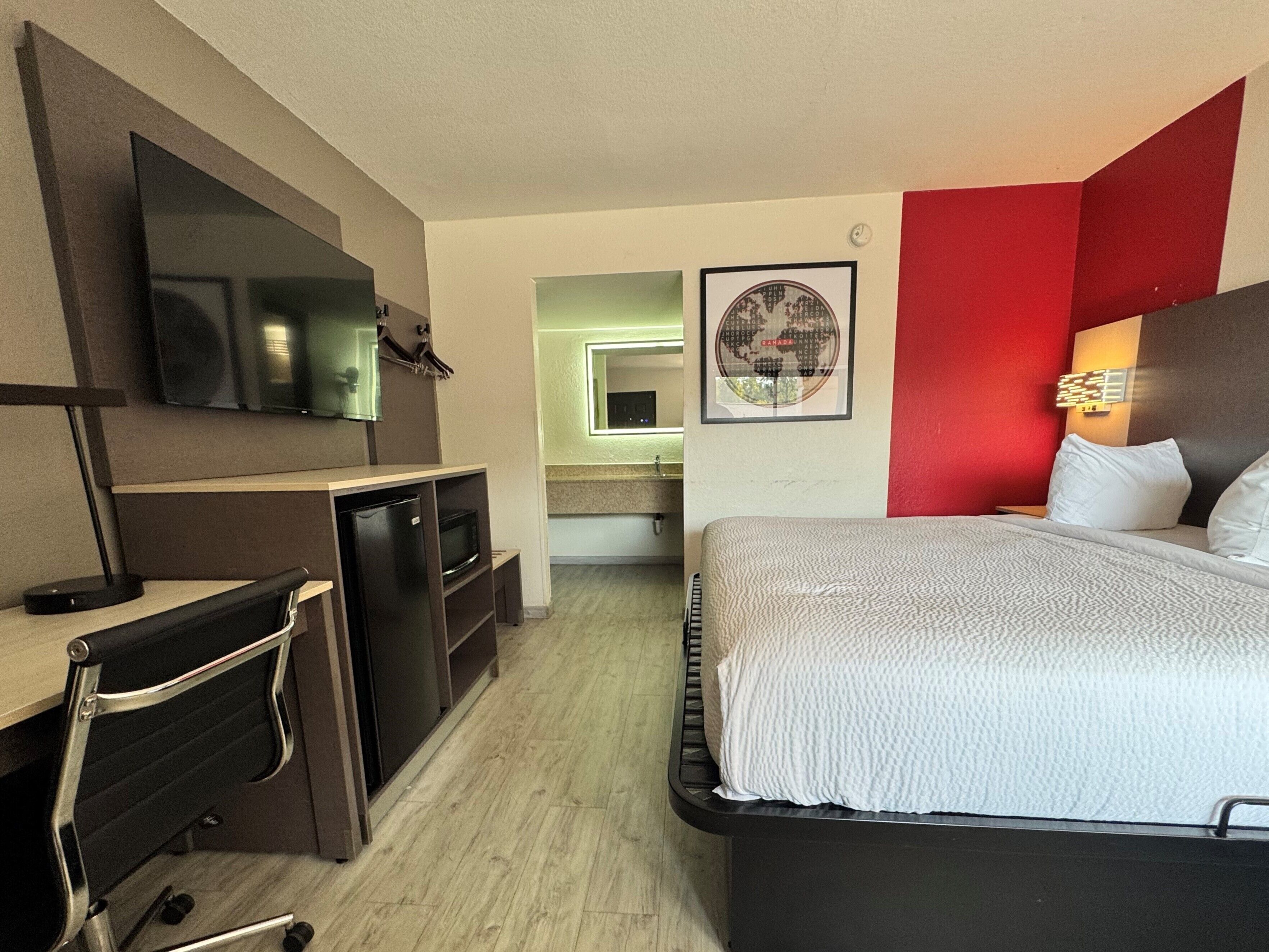 Een hotelkamer met een bed, bureau en een televisie.