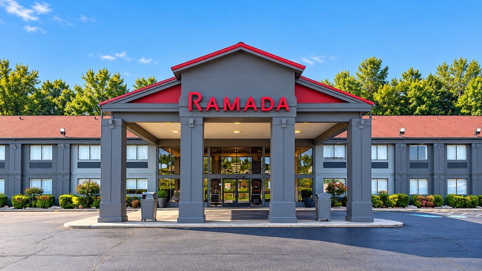 A Ramada hotel entrance with a red roof and grey facade.