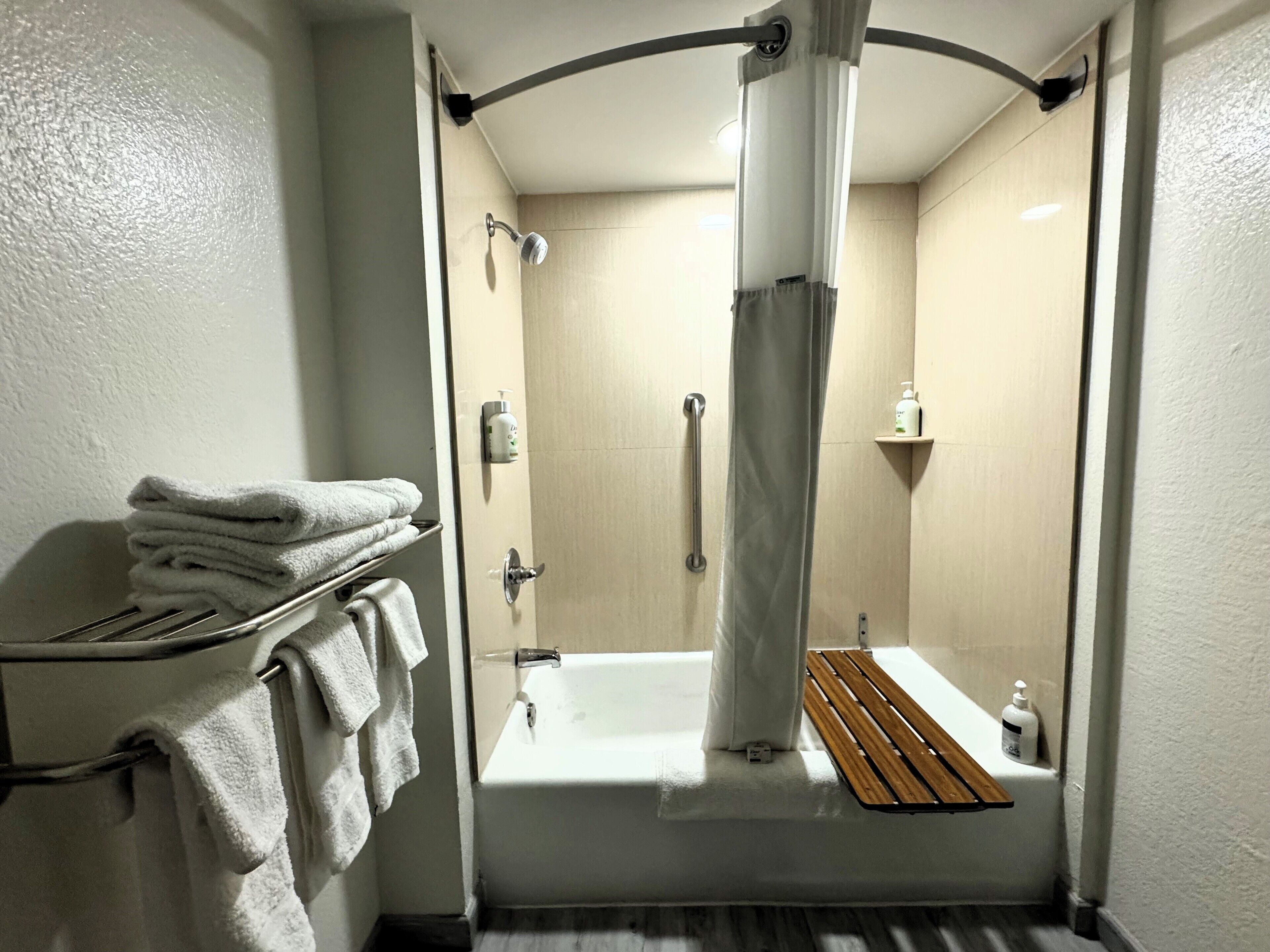 A modern bathroom with a bathtub, a shower, and a towel rack with folded towels.