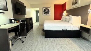 A modern hotel room with a bed, desk, and chair.