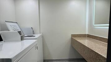 A laundry area with a washing machine, dryer, and a countertop with a sink.