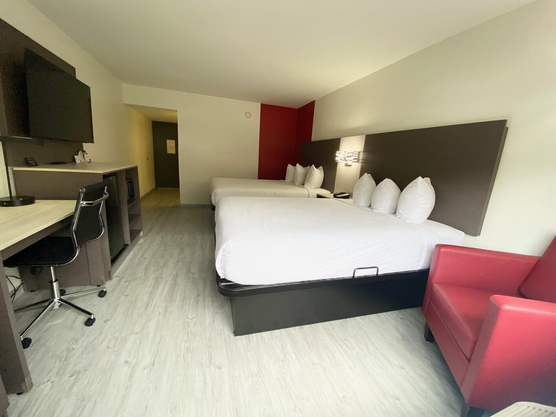 Ein Hotelzimmer mit Bett, Schreibtisch, Stuhl und einer roten Akzentwand.