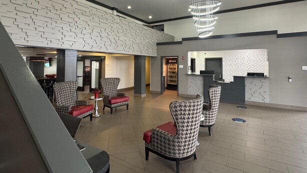 A spacious lobby with houndstooth patterned chairs, a reception desk, and a Pepsi refrigerator.