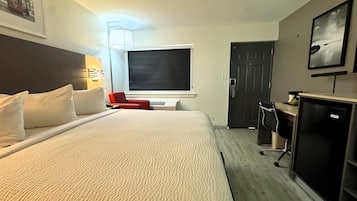 Habitació d'hotel amb un llit gran, una televisió, escriptori i una porta.