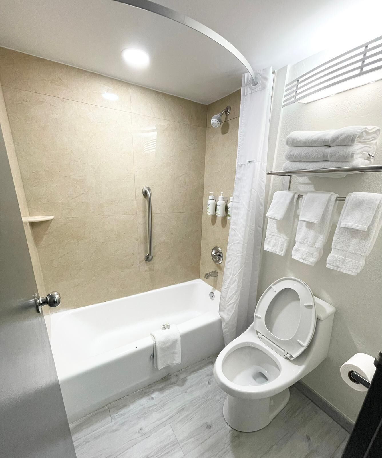A modern bathroom with a bathtub, toilet, and shower.