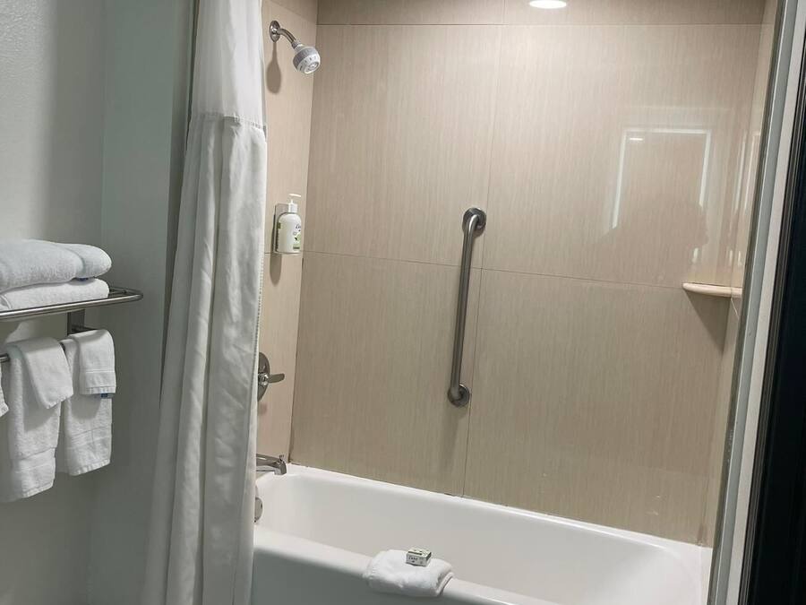 Un baño moderno con cabina de ducha, bañera y un perchero con toallas dobladas.