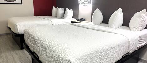 Habitación de hotel con dos camas, una pared de acento roja y una obra de arte con un mapa del mundo.