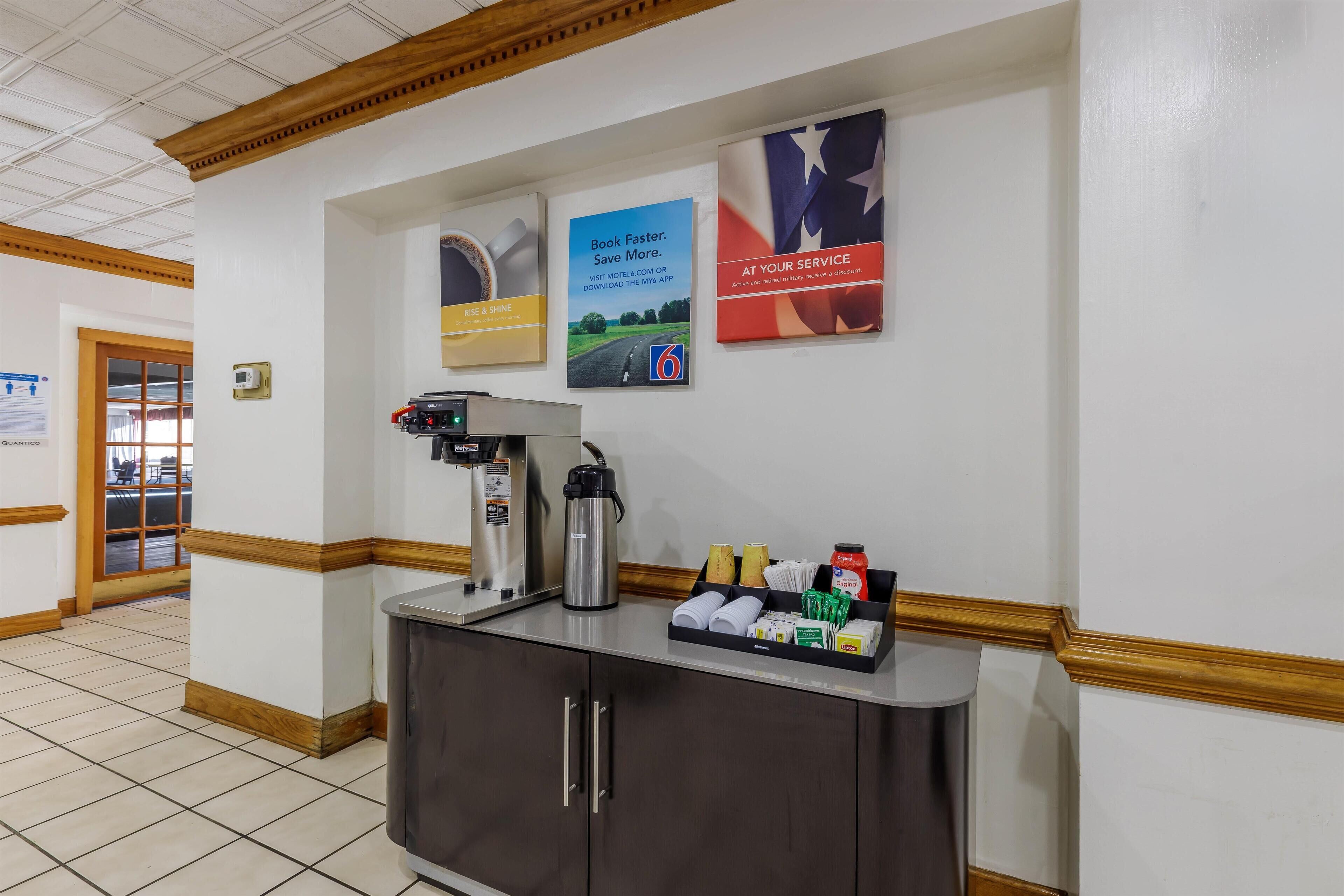 Zona de recepción con máquina de café, dispensador de agua y exhibición de artículos de aseo.