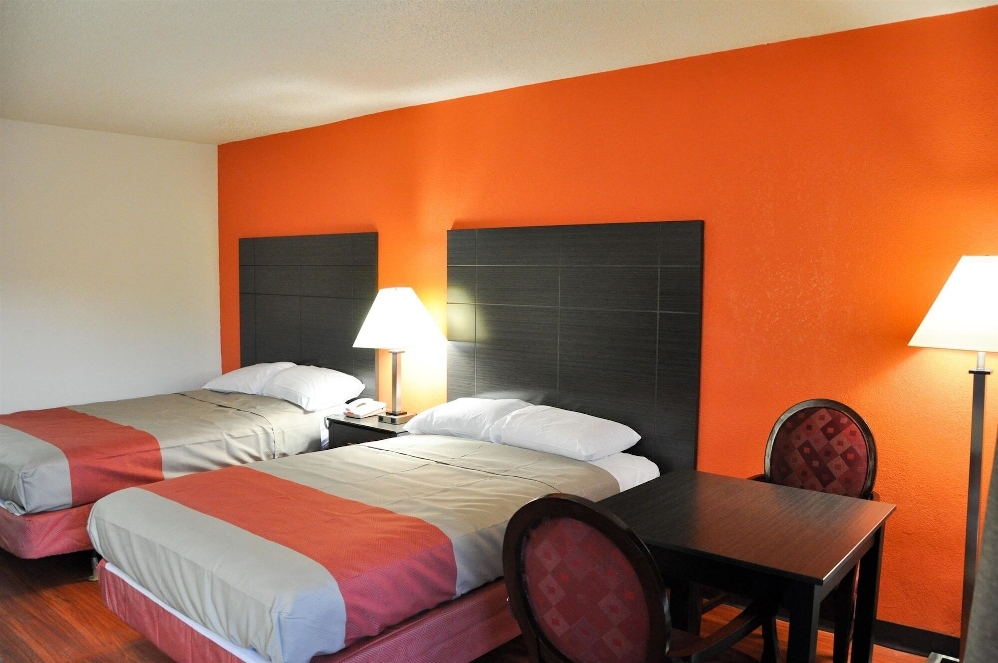 A hotel room with two beds, a desk, and a chair.