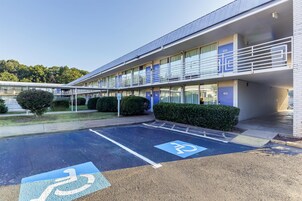 Un edificio moderno con estacionamiento, incluyendo un espacio reservado para personas con discapacidad.