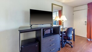 Une chambre d’hôtel équipée d’un bureau, d’une télévision, d’une lampe, d’une chaise et d’une armoire.