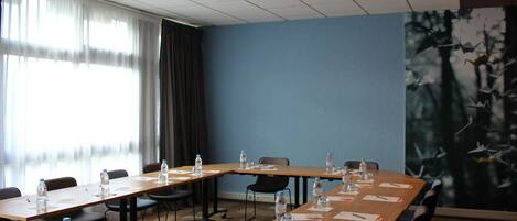 A conference room with long tables, chairs, water bottles, and name cards.