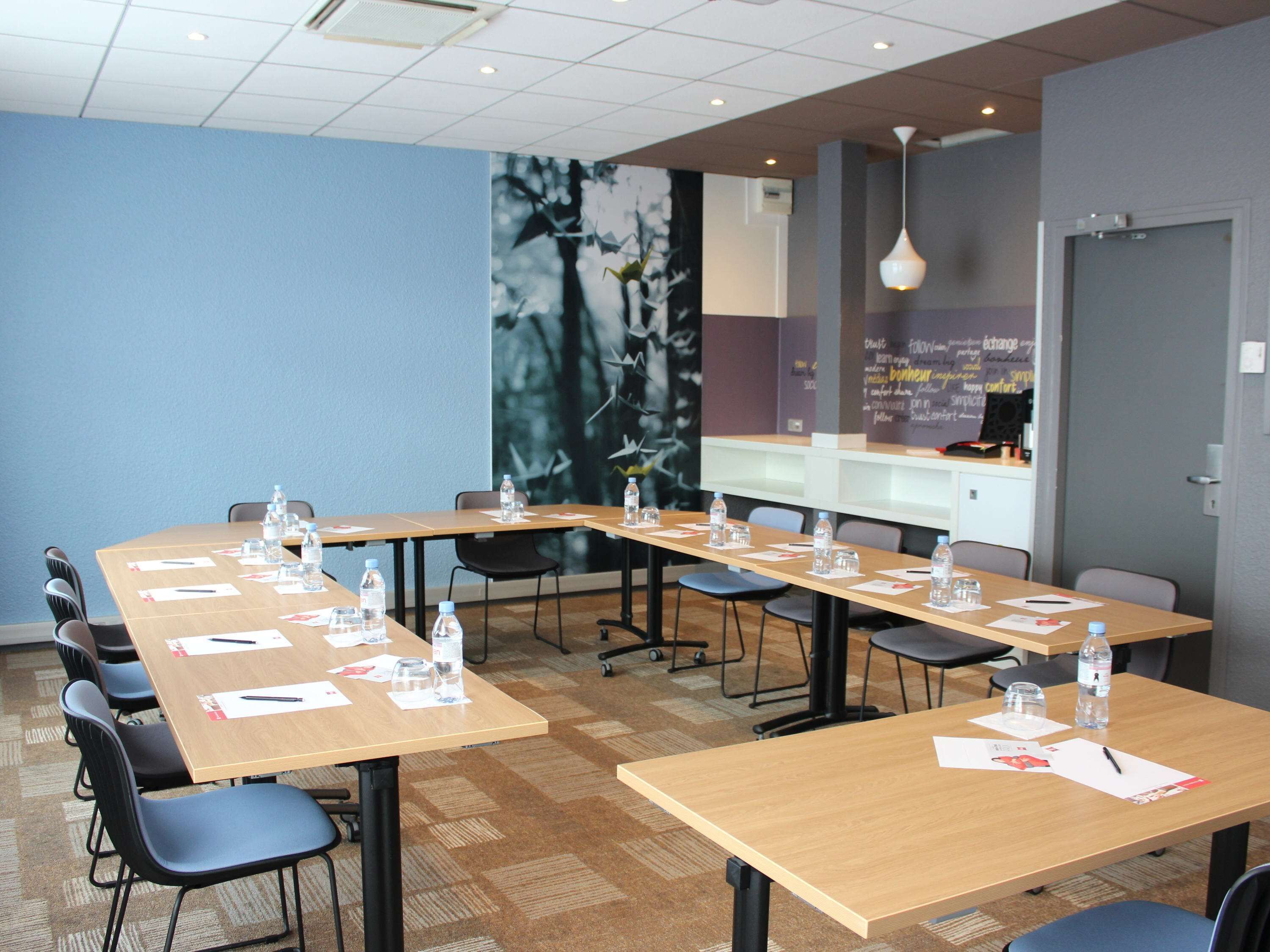 A conference room with long tables, chairs, water bottles, and papers.