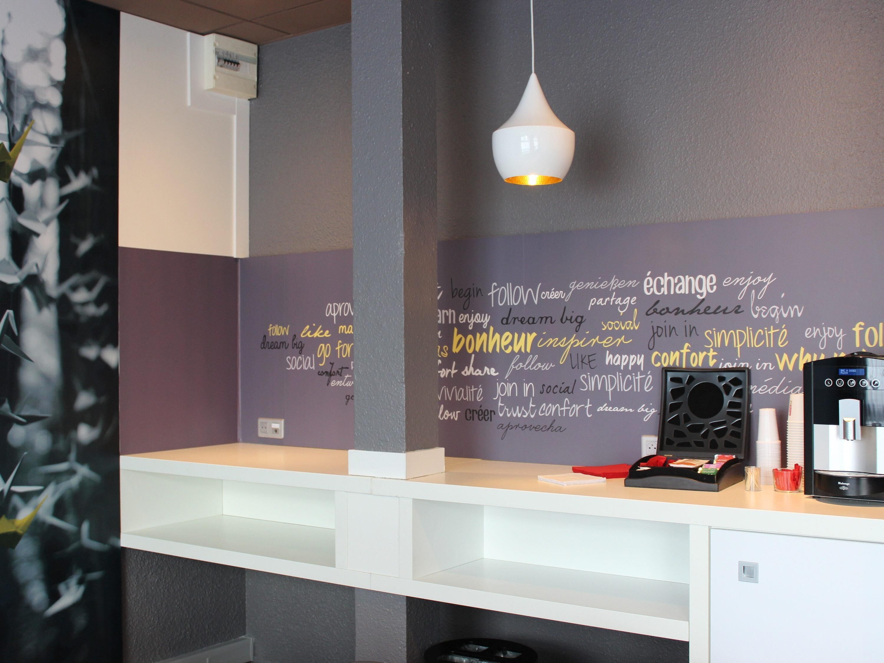 Une pièce moderne avec un bureau blanc, un luminaire suspendu et un mur orné de mots inspirants.