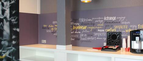 A modern room with a white desk, a hanging pendant light, and a wall with motivational words.