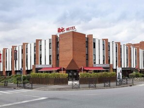 A hotel with a prominent 'ibis Hotel' sign, a modern brick facade, and a restaurant named 'ibis Kitchen' at the ground level. - Ibis Evry-Courcouronnes (Évry-Courcouronnes)