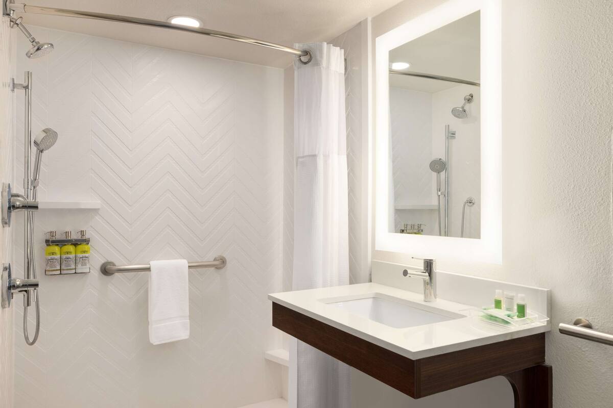 A modern bathroom with a shower, a vanity with a mirror, and a towel rack.