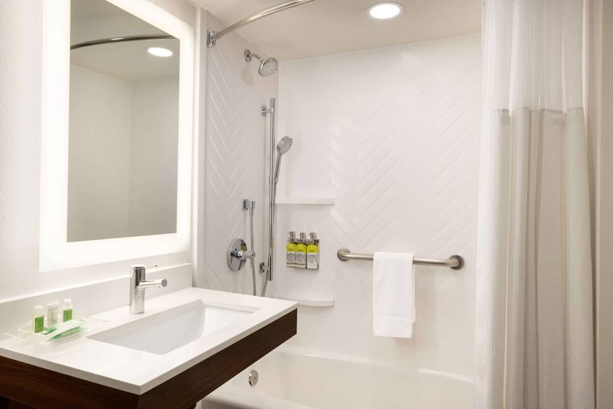 A bathroom with a white sink, mirror, and shower.