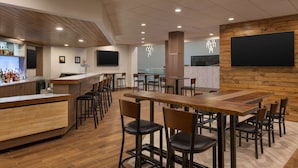 Un restaurante moderno con barra de madera y varias mesas y sillas.