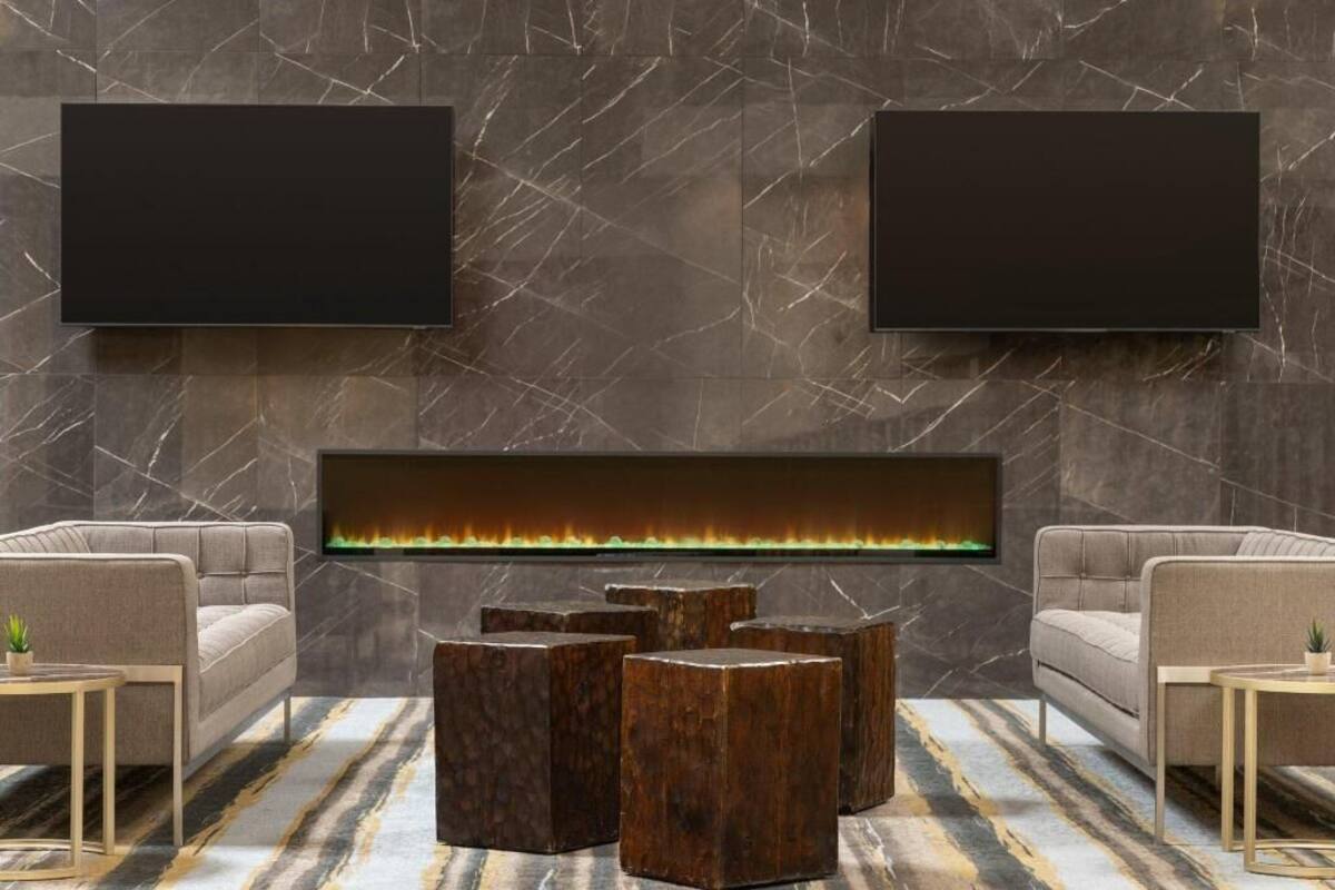 A modern living room with a fireplace, two sofas, and a flat-screen TV mounted on the wall.