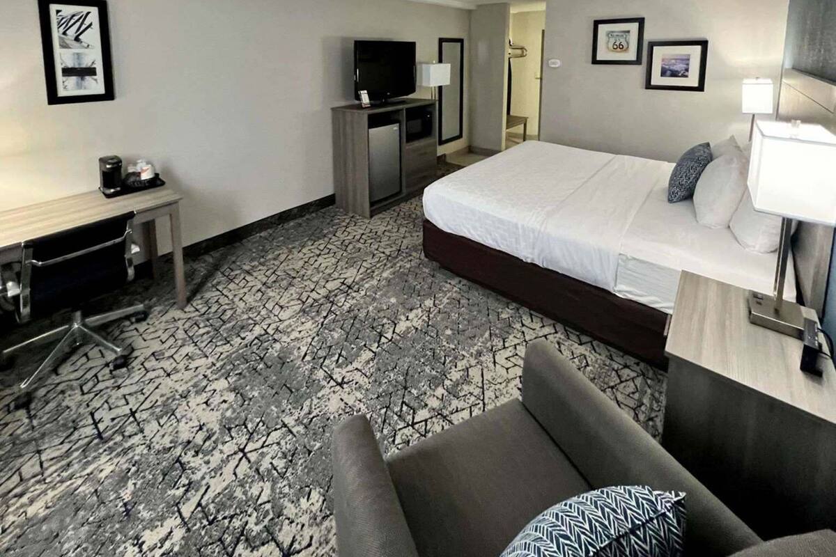 Una habitación de hotel con cama, escritorio, televisión y silla.