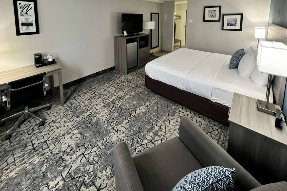 Una habitación de hotel con una cama, un escritorio, un televisor y una silla.