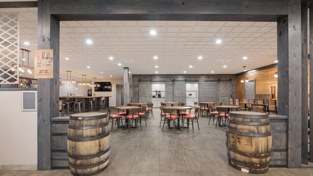 Un restaurant spacieux, décoré de barils, de tables et de chaises en bois.